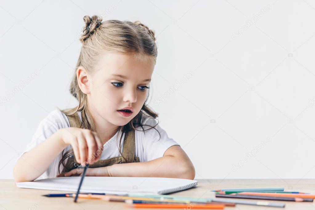 adorable little schoolgirl drawing with color pencils isolated on white