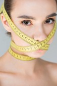 portrét atraktivní mladé ženy s uzavřenému ústa páskou měření izolované na šedém pozadí 