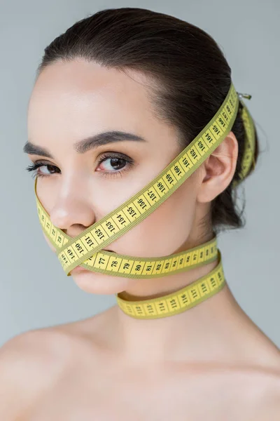 灰色の背景に分離測定テープで口を閉じて 魅力的な若い女性の肖像画  — 無料ストックフォト