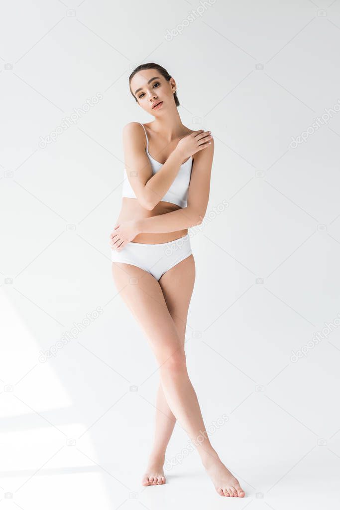 young attractive caucasian woman in white lingerie posing isolated on gray background 