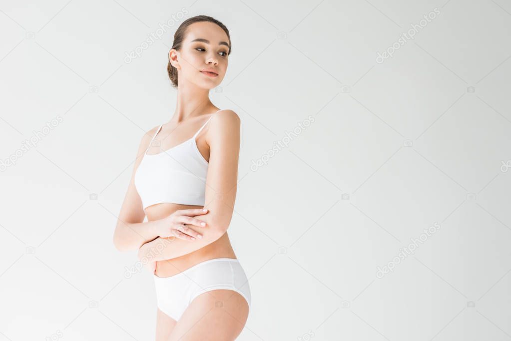 attractive caucasian woman in white lingerie with folded arms isolated on gray background 
