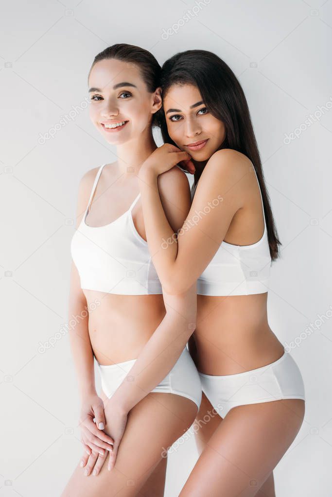 smiling multicultural women looking at camera isolated on gray background 