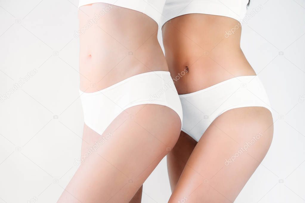 cropped image of two women in white lingerie isolated on gray background 