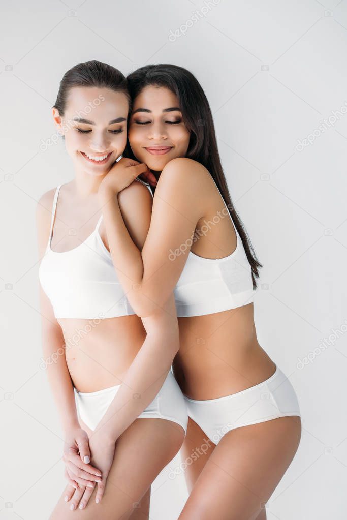 smiling multicultural women embracing isolated on gray background 