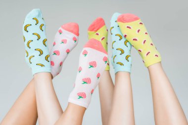 partial view of female feet in colorful fruity socks, isolated on grey clipart