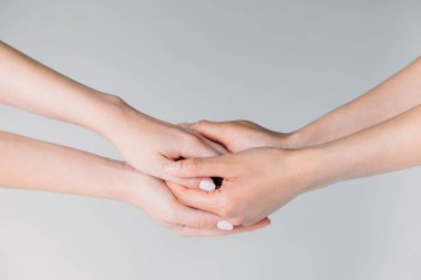 partial view of female friends holding hands, isolated on grey clipart
