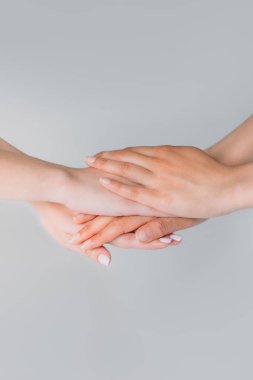 cropped view of girls holding hands together, isolated on grey clipart