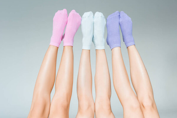 обрезанное изображение женских ног в различных красочных носках, выделенных на сером фоне
 