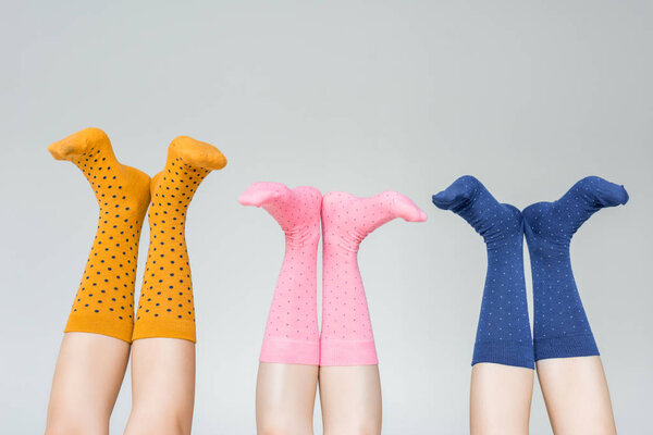 partial view of female legs in different colorful socks isolated on gray background 