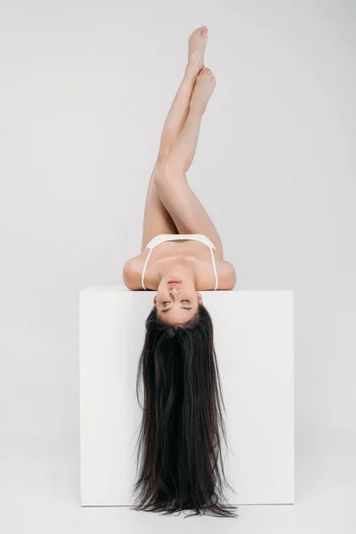 Brunette Asian Girl Lying White Cube Isolated Grey — Free Stock Photo
