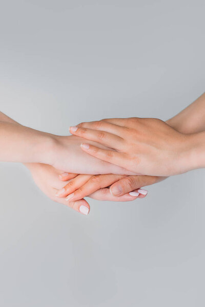 cropped view of girls holding hands together, isolated on grey