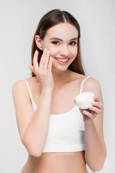Elegante Chica Sonriente Aplicando Crema Facial Aislado Gris — Foto de Stock