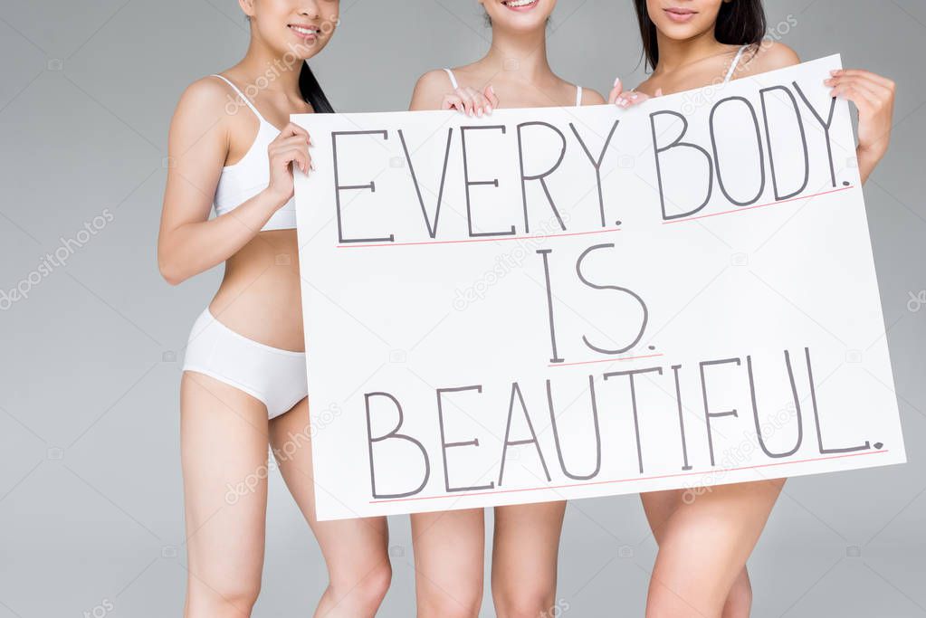 cropped image of smiling multicultural women holding banner with lettering everybody is beautiful isolated on gray background 
