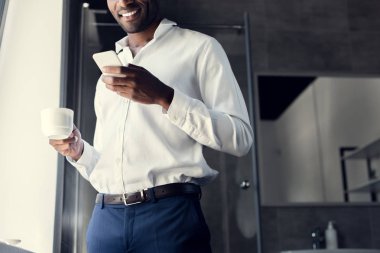 genç işadamı kahve molası sırasında smartphone kullanarak beyaz gömlek gülümseyen in atış kırpılmış