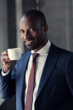 happy young businessman with cup of coffee looking at camera clipart