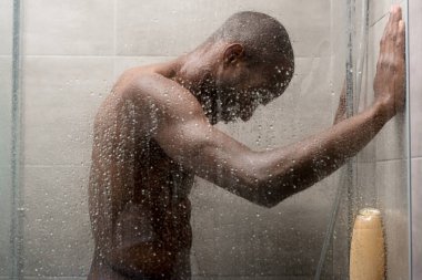 yakışıklı genç Afro-Amerikan erkek duşta vücut yıkama yan görünüm 