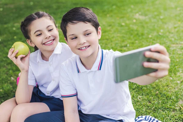 Crianças Felizes Idade Escolar Tomando Selfie Enquanto Sentado Grama Parque — Fotografia de Stock