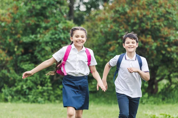 公園で実行しているバックパックと幸せな小学生 — ストック写真