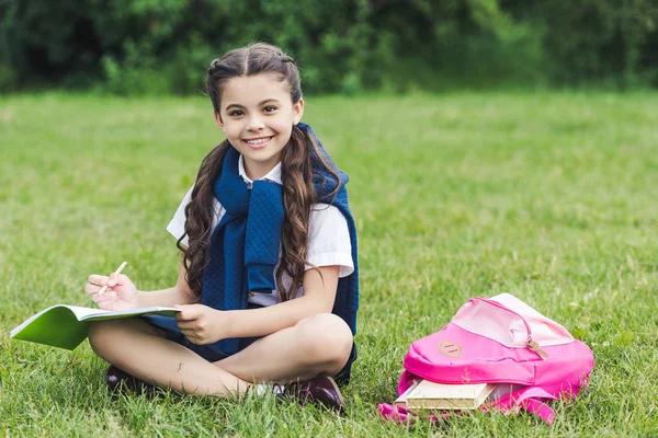 公園の芝生の上に座って宿題美しい女子高生 — ストック写真