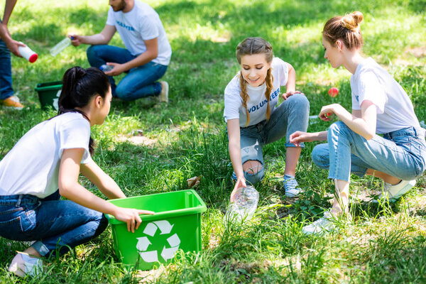 young volunteers cleaning park with recycling boxes