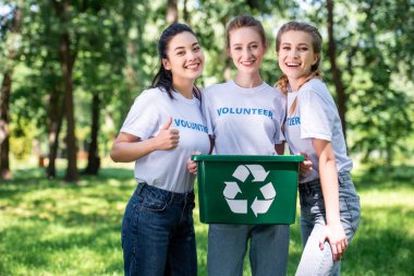 young female volunteers with recycling box showing thumb up clipart