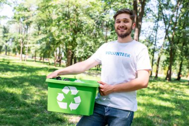 plastik çöp geri dönüşüm kutusu tutan genç mutlu gönüllü