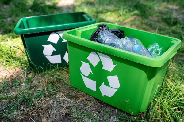 зеленые коробки для переработки с пластиковым мусором, стоящим на газоне
