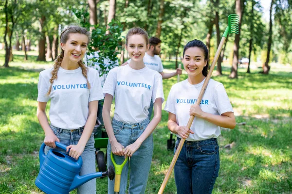 Unga Kvinnliga Volontärer Med Vattenkanna Spade Och Kratta Stående Park — Stockfoto