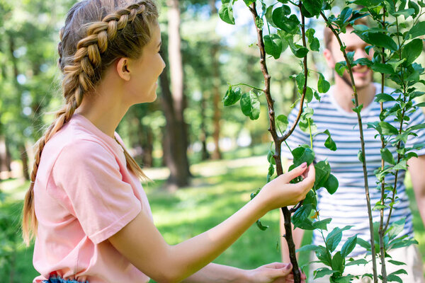 young couple with green tree in park