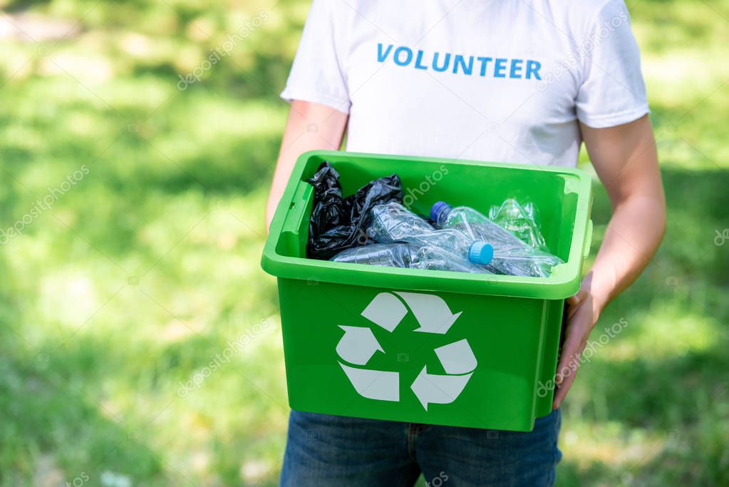 partial view of male volunteer holding recycling box with plastic waste