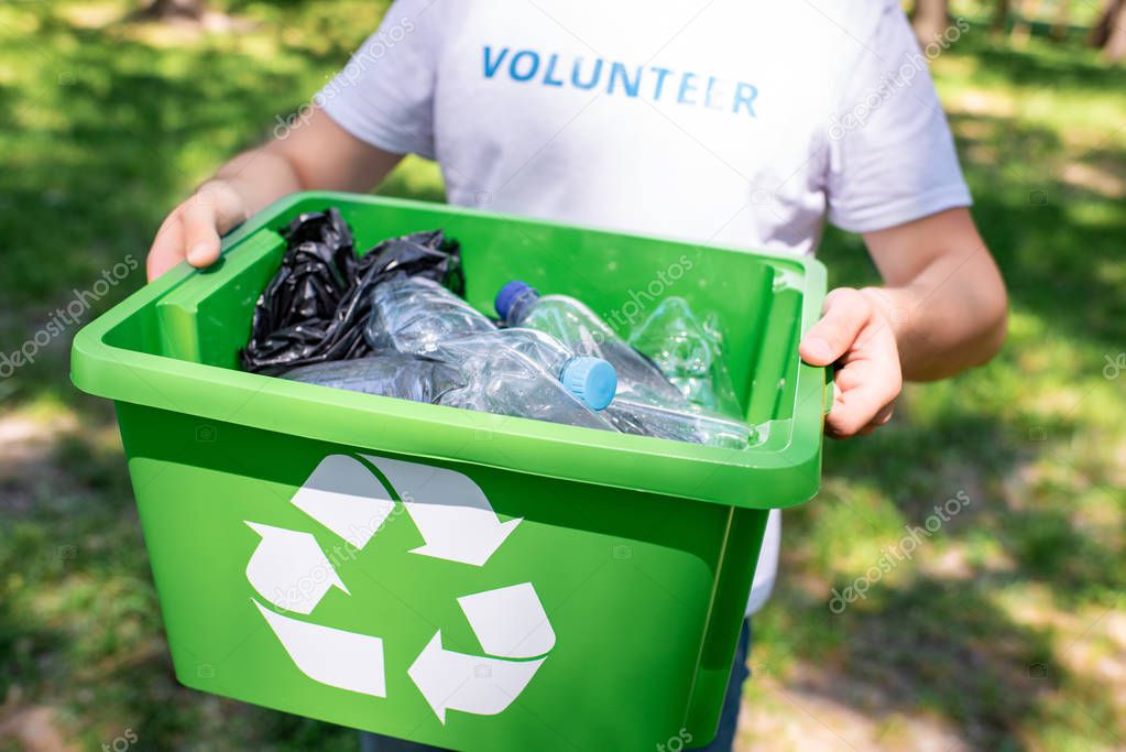 cropped view of volunteer holding recycling box with plastic trash