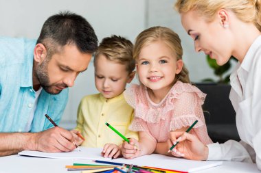 happy parents with cute little children drawing together at home  clipart