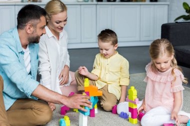 mutlu anne evde renkli bloklar ile oynayan sevimli küçük çocuklar ile