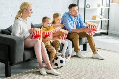 patlamış mısır yemek ve evde tv izlerken iki çocuklu aile