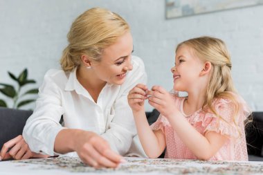 mutlu anne ve diğer her evde puzzle parçaları ile oynarken gülümseyen kız