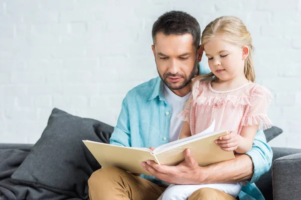 父亲和可爱的小女儿在家里看书 — 图库照片