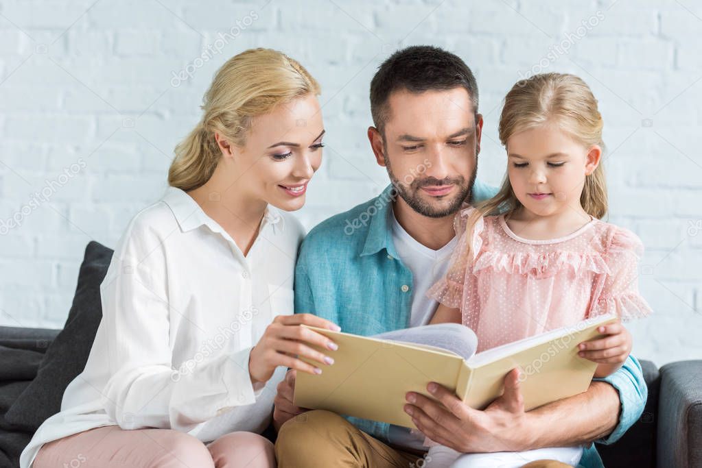 happy family with one child reading book together at home