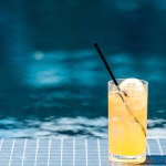 Close-up shot van glas van smakelijke oranje cocktail op zwembad