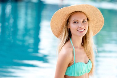 hasır şapka ve havuz başı kameraya bakarak bikini çekici genç kadın