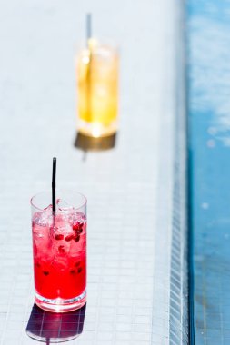 close-up shot of glasses of cocktails on poolside clipart