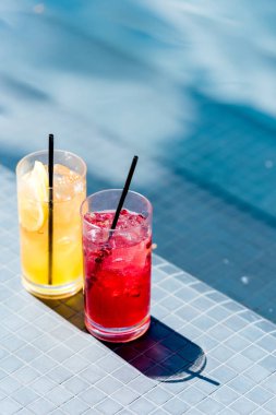 close-up shot of glasses of delicious fruit cocktails on poolside clipart