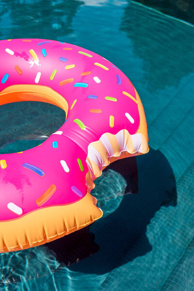 close-up shot of inflatable ring in shape of bitten donut floating in swimming pool