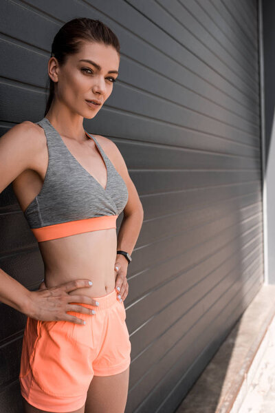 smiling young sportswoman posing in sportswear and looking at camera