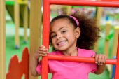 Lächelnd lockiges afrikanisch-amerikanisches Kind klettert auf Treppe auf Spielplatz 