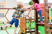 Zwei multiethnische kleine Kinder klettern und spielen auf Spielplatz 