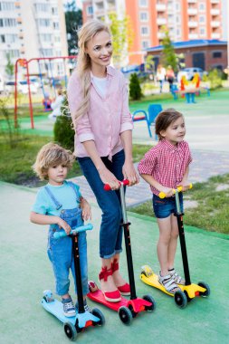 mutlu anne sevimli oğlu ve kızı, bahçesi ile tekme scooter sürme 