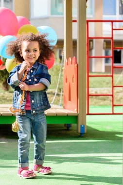 kıvırcık Afro-Amerikan küçük çocuk parkında renkli balonlar tutan gülümseyerek 