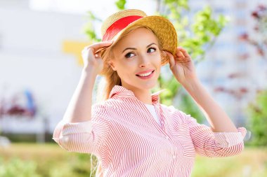 arka plan bulanık üzerinde hasır şapkalı gülümseyen genç kadın portresi 