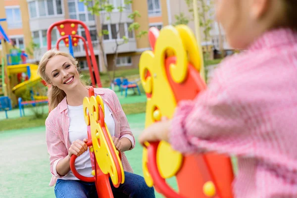 Beskuren Bild Flicka Som Rider Gunghäst Med Leende Mamma Lekplats — Stockfoto