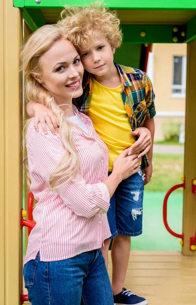 Anne kucaklayan sevimli kıvırcık oğul Bahçesi, gülümseyen 